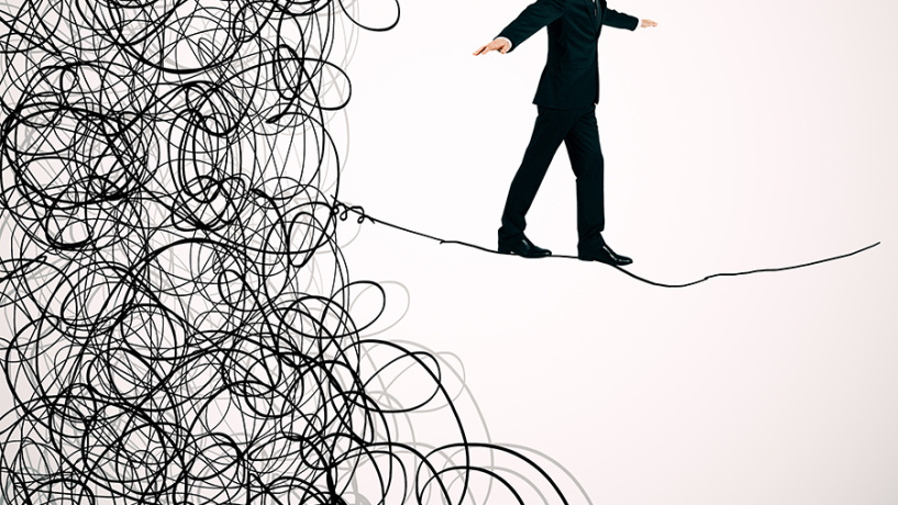 Business person balancing on chaotic tight rope