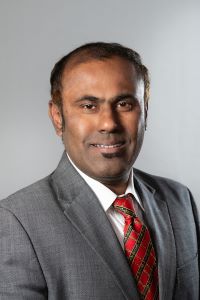 Photo of Viswanathan Balakrishnan, Michigan Ross EMBA student wearing a gray suit with a white shirt and a red tie. 
