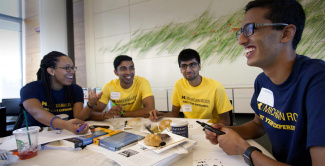 group of people sitting around a able eating snacks and working on a project