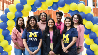 Women in Ross shirts standing in front of maize and blue balloons