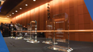 Row of glass award trophies displayed on a table at an indoor event.